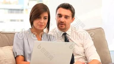 年轻夫妇在沙发上用笔记本电脑